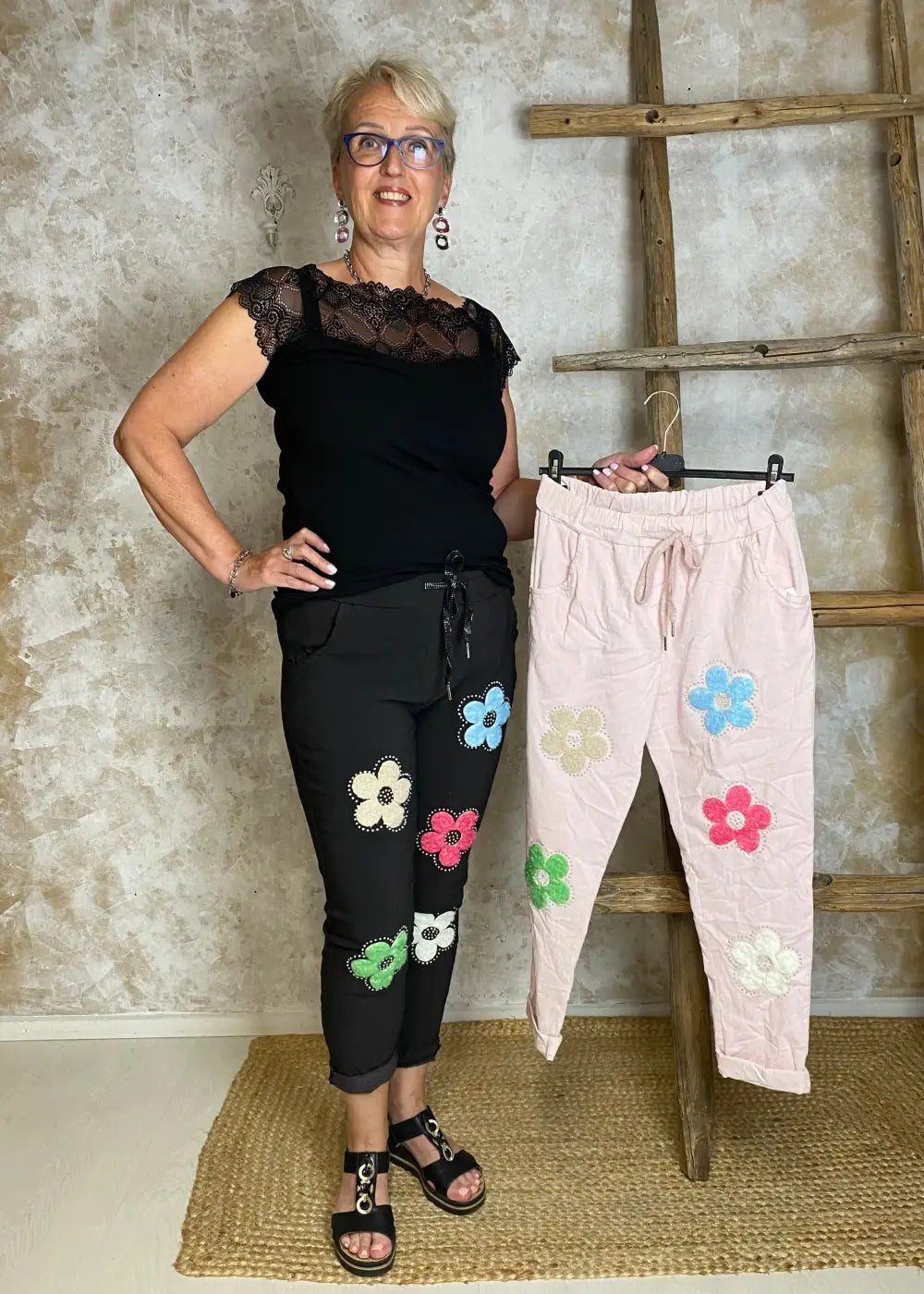 Naisten stretch-housut kukkakuvioilla ja strasseilla, kuminauhavyötärö, taskut edessä, kapenevat lahkeet.