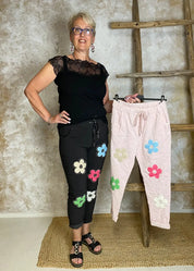 Naisten stretch-housut kukkakuvioilla ja strasseilla, kuminauhavyötärö, taskut edessä, kapenevat lahkeet.