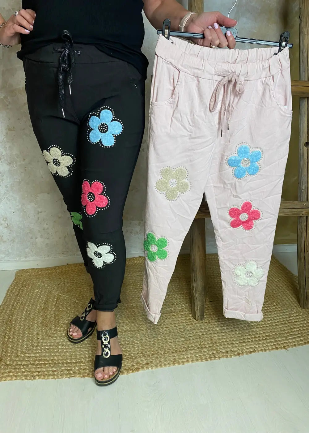 Naisten stretch-housut kukkakuvioilla ja strasseilla, kuminauhavyötärö, taskut edessä, kapenevat lahkeet.