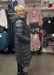 Naisten musta pitkä toppatakki, suora malli, huppu, sivuvetoketjut, lämmin ja tyylikäs valinta talven kylmiin päiviin.