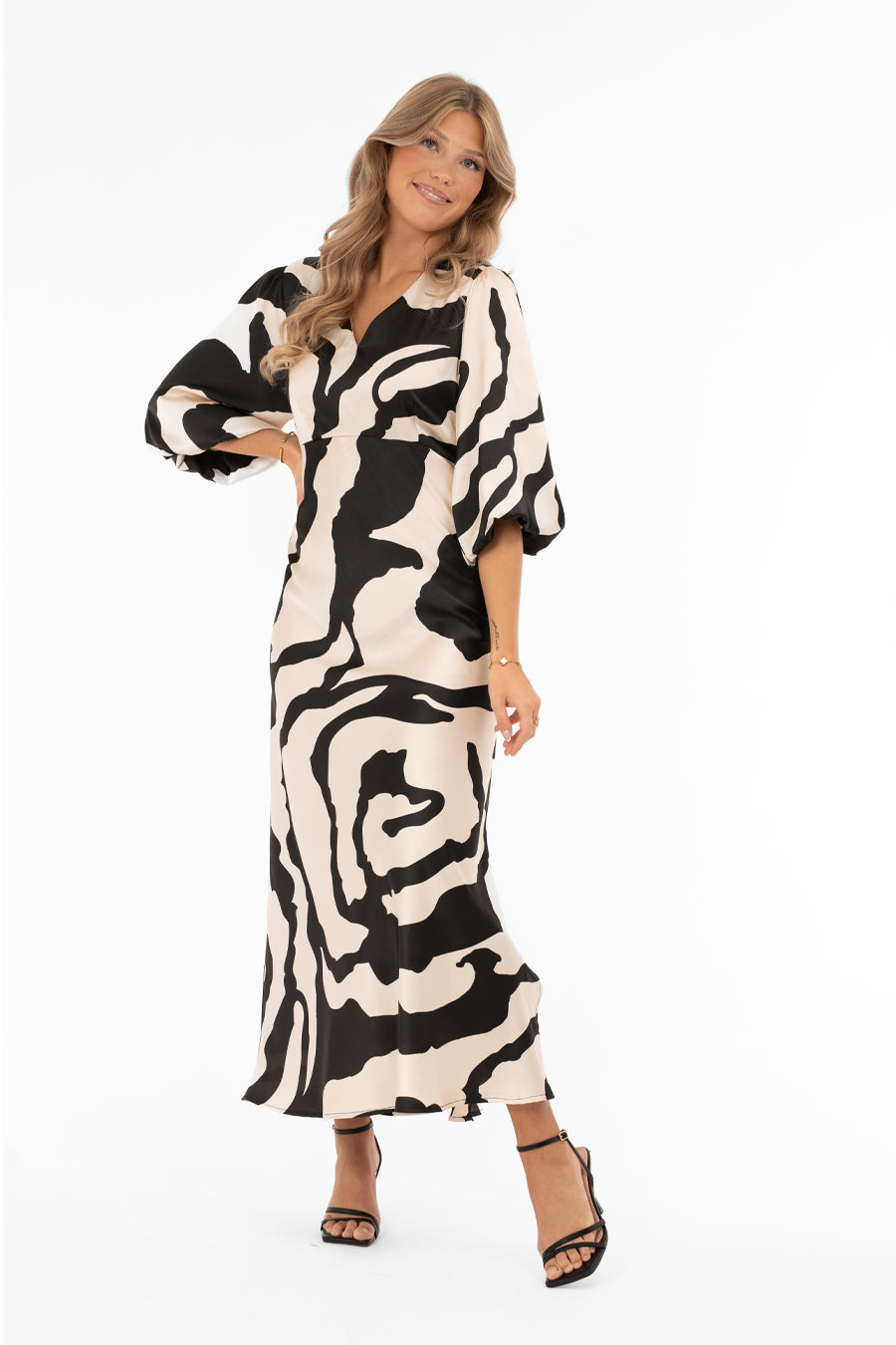 Naisten ylellinen satiinimekko shamppanjan sävyisellä pohjalla, musta abstrakti kuviointi, leveät puhvihihat, poikkileikkaus vyötäröllä, levenevä helma ja halkio toisella sivulla, V-pääntie