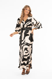 Naisten ylellinen satiinimekko shamppanjan sävyisellä pohjalla, musta abstrakti kuviointi, leveät puhvihihat, poikkileikkaus vyötäröllä, levenevä helma ja halkio toisella sivulla, V-pääntie