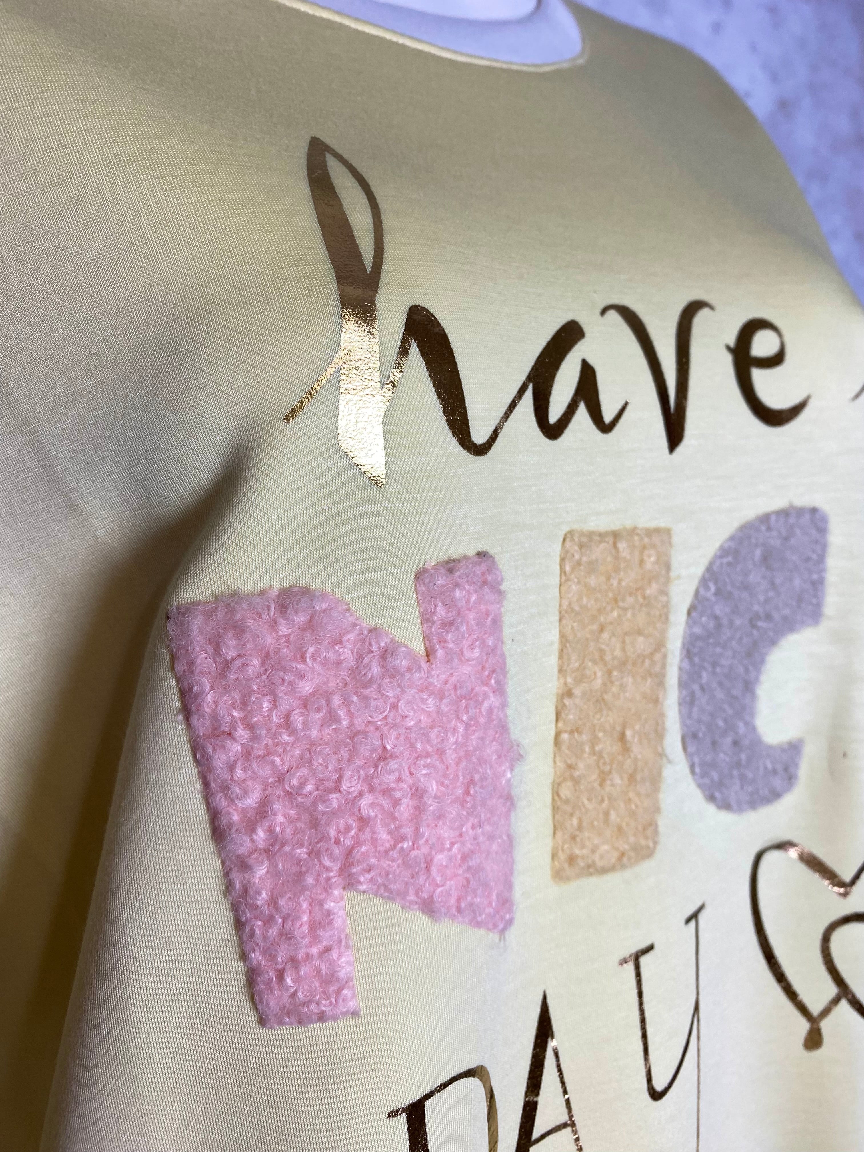 Naisten keltainen collegepaita pehmeästä ja joustavasta materiaalista, edessä “Have a nice day” -teksti, alaspäin kapeneva malli, pitkät hihat ja O-pääntie