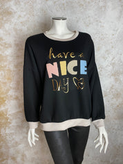 Naisten valkoinen collegepaita pehmeästä ja joustavasta materiaalista, edessä “Have a nice day” -teksti, alaspäin kapeneva malli, pitkät hihat ja O-pääntie