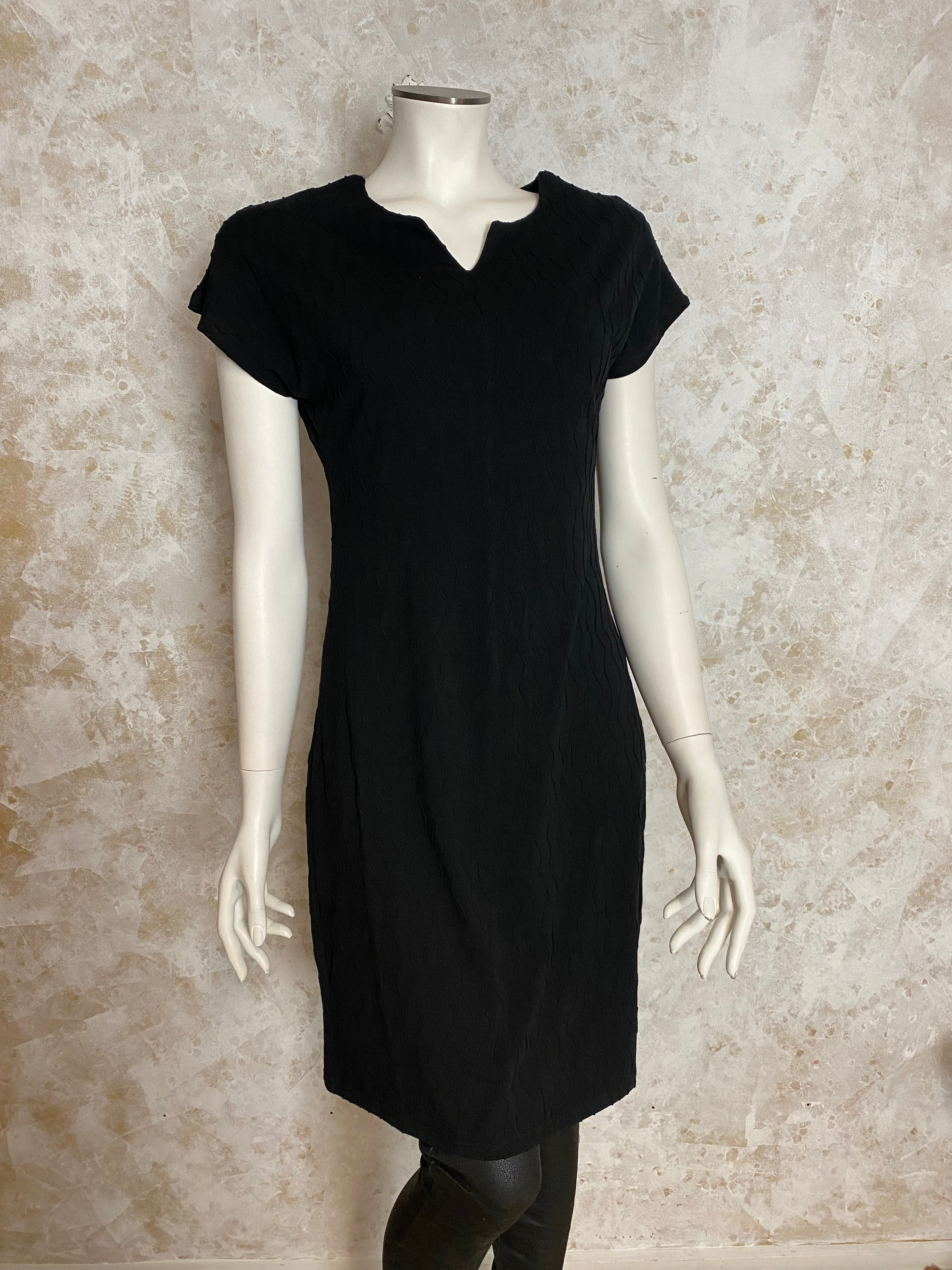 Naisten pikkumusta mekko, tekstuurinen pinta, paksu joustava materiaali, naisellinen malli, O-pääntie pienellä V-aukolla ja holkkihihat