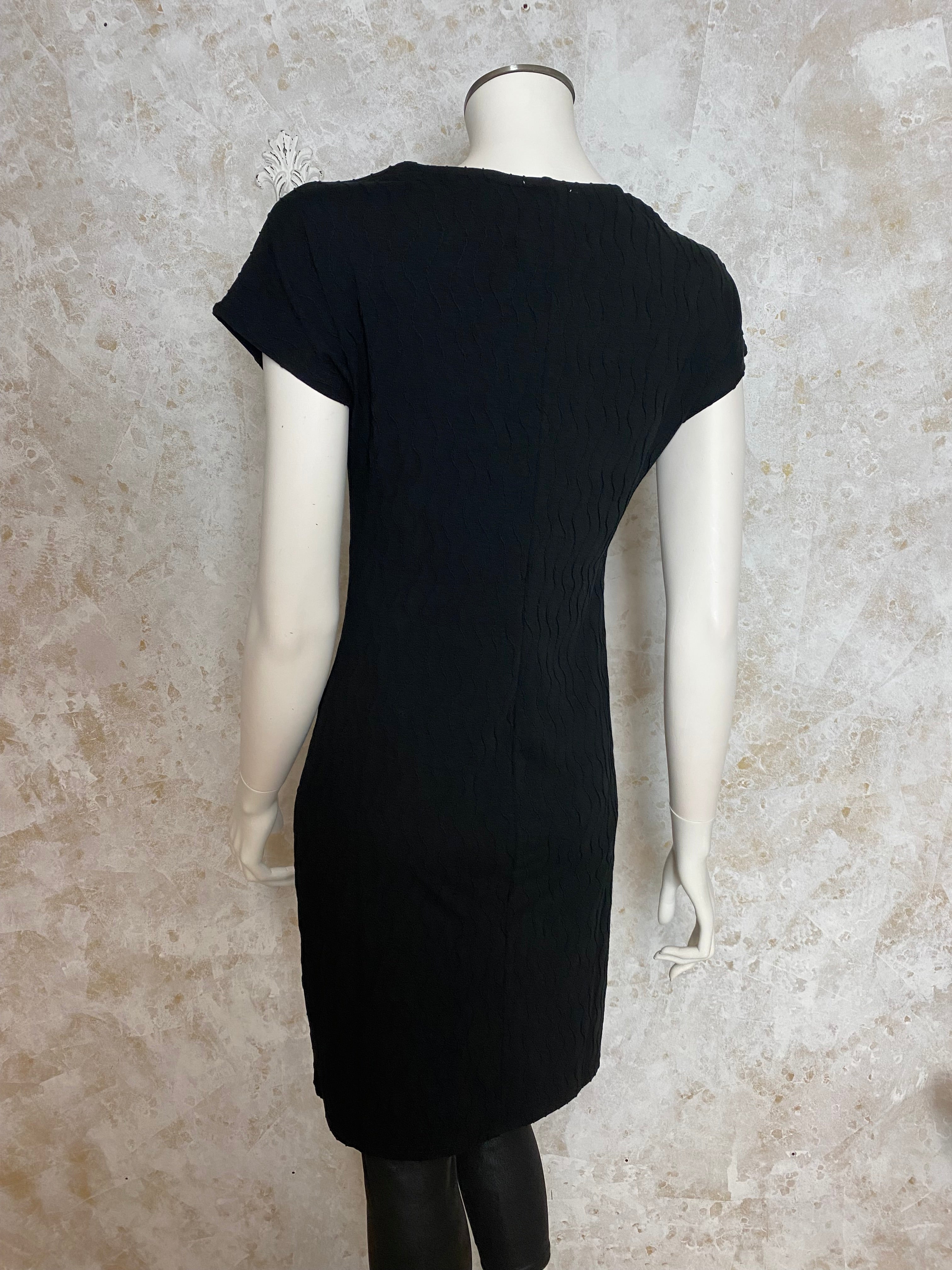 Naisten pikkumusta mekko, tekstuurinen pinta, paksu joustava materiaali, naisellinen malli, O-pääntie pienellä V-aukolla ja holkkihihat