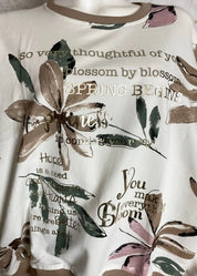 Kukkakuvioinen collegepaita kullan sävyisellä tekstiprintillä edessä, pehmeä joustava materiaali, resorit ja pussimainen helma.