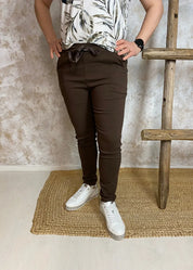 Naisten rennot stretch-housut ruskeana, korkea kuminauhavyötärö kiristysnarulla, edessä taskut ja kapeneva lahje