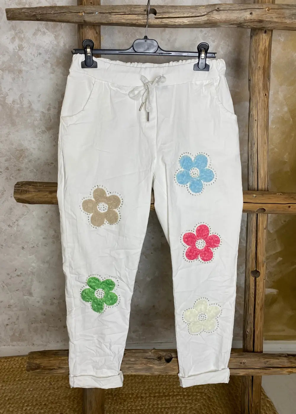 Naisten stretch-housut kukkakuvioilla ja strasseilla, kuminauhavyötärö, taskut edessä, kapenevat lahkeet.