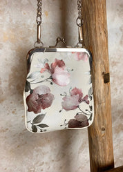 Kukkakuvioinen olkalaukku ketju- ja säädettävällä hihnalla, klipsikiinnitys ja hopeansävyiset yksityiskohdat