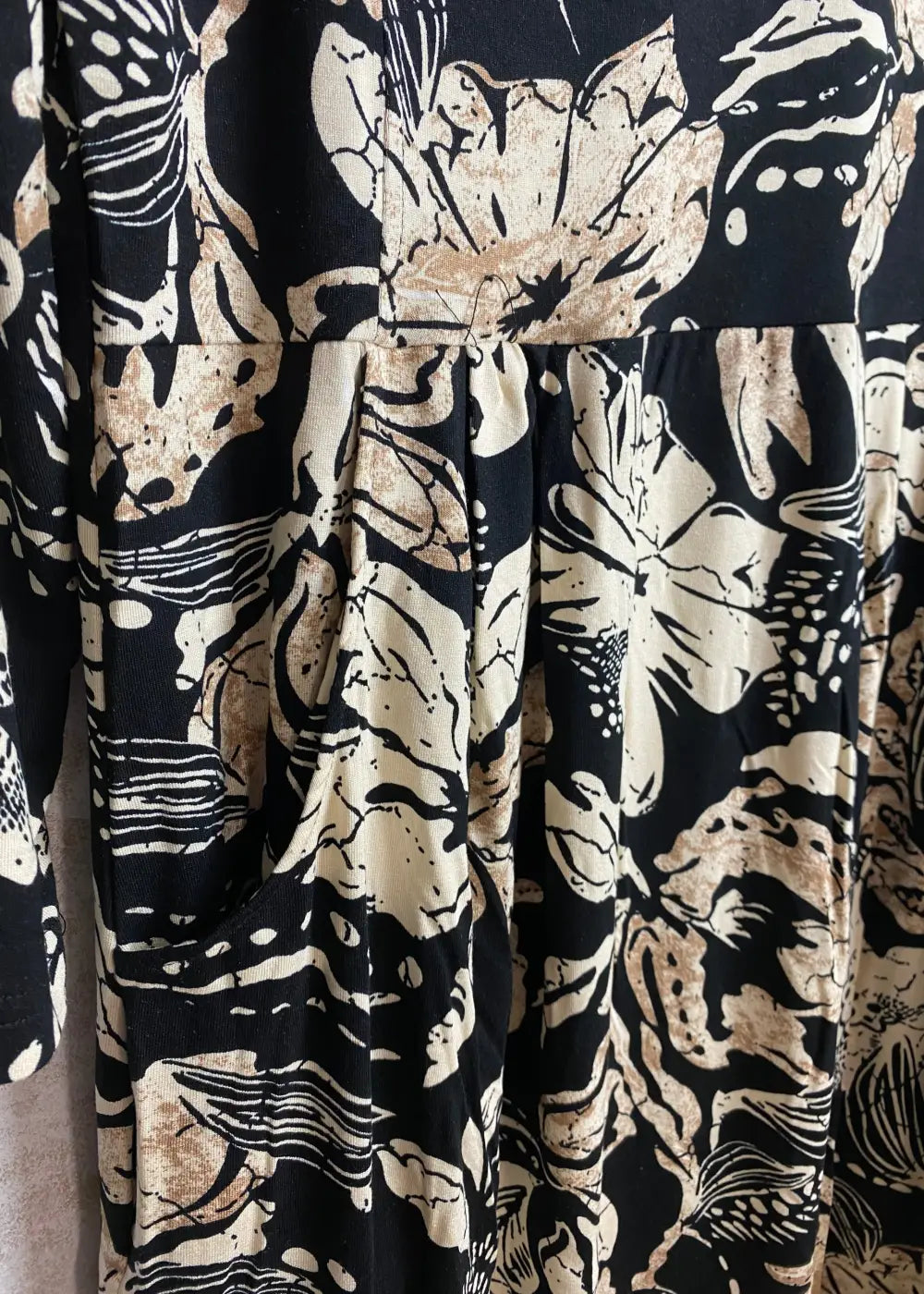 Hiekanvärinen kuviollinen mekko, jossa O-pääntie, vyötäröllä poikkileikkaus, taskut, vajaamittaiset hihat ja levenevä helma