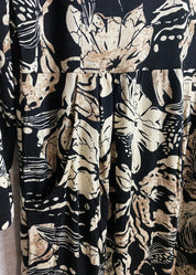 Hiekanvärinen kuviollinen mekko, jossa O-pääntie, vyötäröllä poikkileikkaus, taskut, vajaamittaiset hihat ja levenevä helma