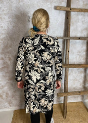 Hiekanvärinen kuviollinen mekko, jossa O-pääntie, vyötäröllä poikkileikkaus, taskut, vajaamittaiset hihat ja levenevä helma