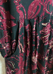 Viininpunainen kuviollinen mekko, jossa O-pääntie, vyötäröllä poikkileikkaus, taskut, vajaamittaiset hihat ja levenevä helma