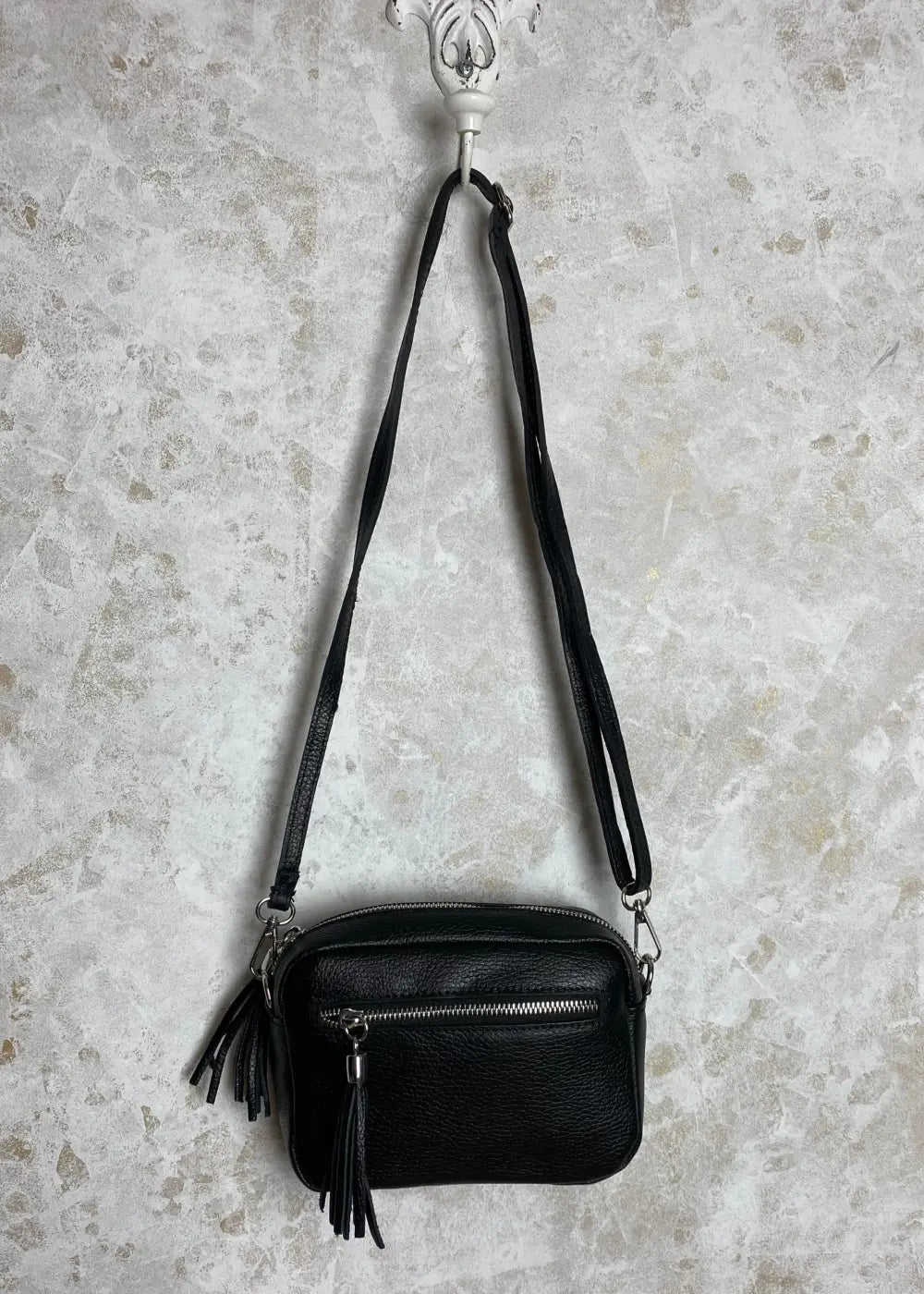 Tyylikäs nahkalaukku aidosta nahasta, säädettävällä hihnalla, vetoketjutaskuilla ja hopeisilla yksityiskohdilla.