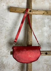 Rohkea punainen nahkalaukku kimaltavalla kuosilla, säädettävä ja irrotettava nahkahihna, vetoketju, kangasvuori ja sisätasku