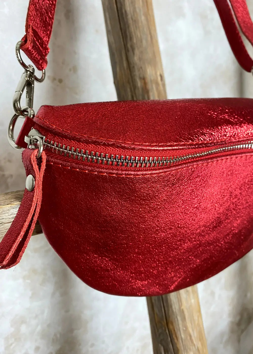 Rohkea punainen nahkalaukku kimaltavalla kuosilla, säädettävä ja irrotettava nahkahihna, vetoketju, kangasvuori ja sisätasku