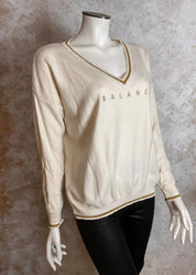 Pehmeä neule V-pääntiellä, glitter-painatuksella ja alaspäin kapenevalla mallilla, laskettu olkalinja ja kultakirjailut resoreissa