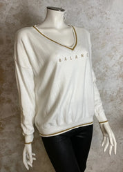 Pehmeä neule V-pääntiellä, glitter-painatuksella ja alaspäin kapenevalla mallilla, laskettu olkalinja ja kultakirjailut resoreissa