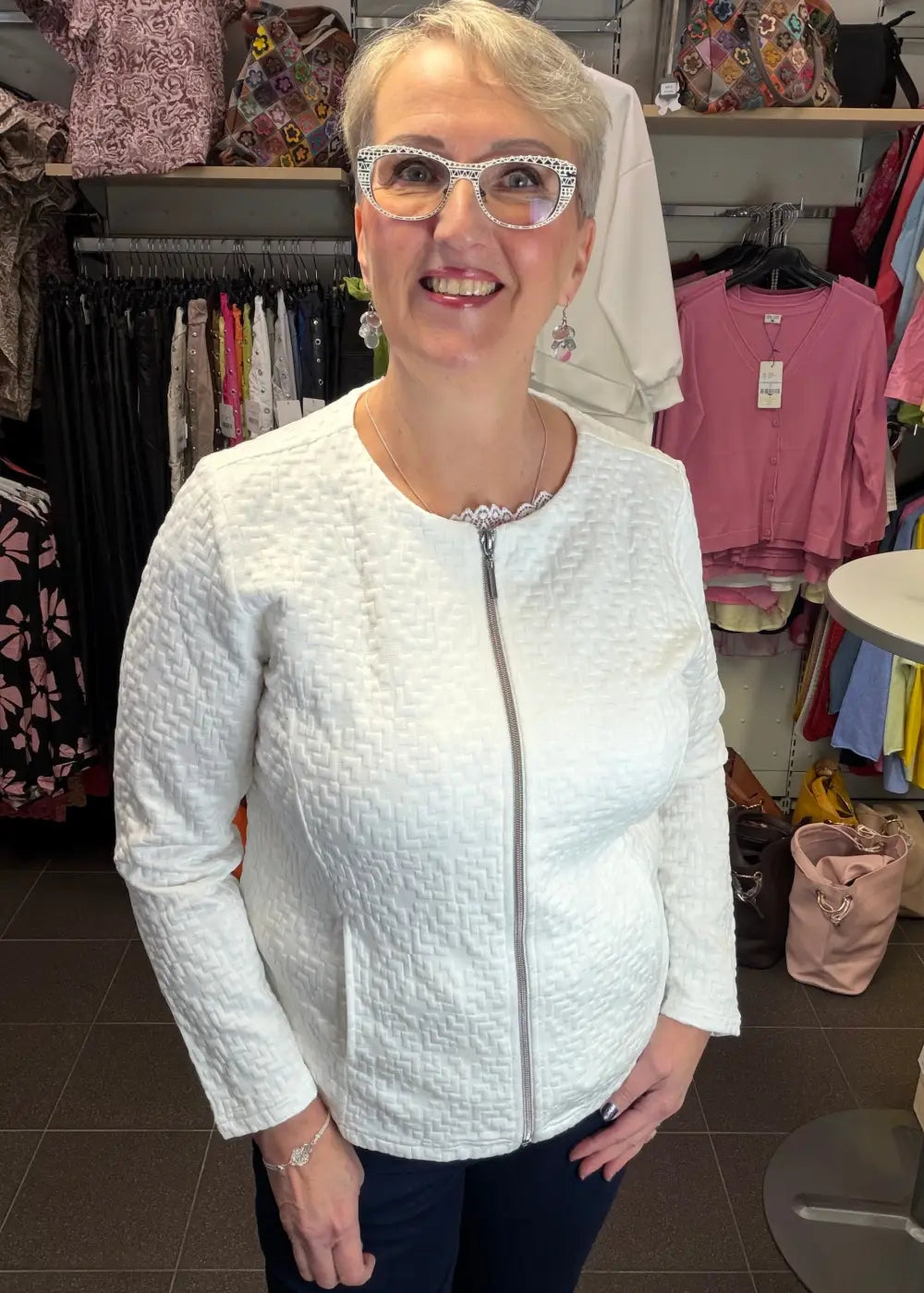 Valkoinen tekstuuripintainen neulosjakku paksusta joustavasta materiaalista, vetoketju edessä ja taskut