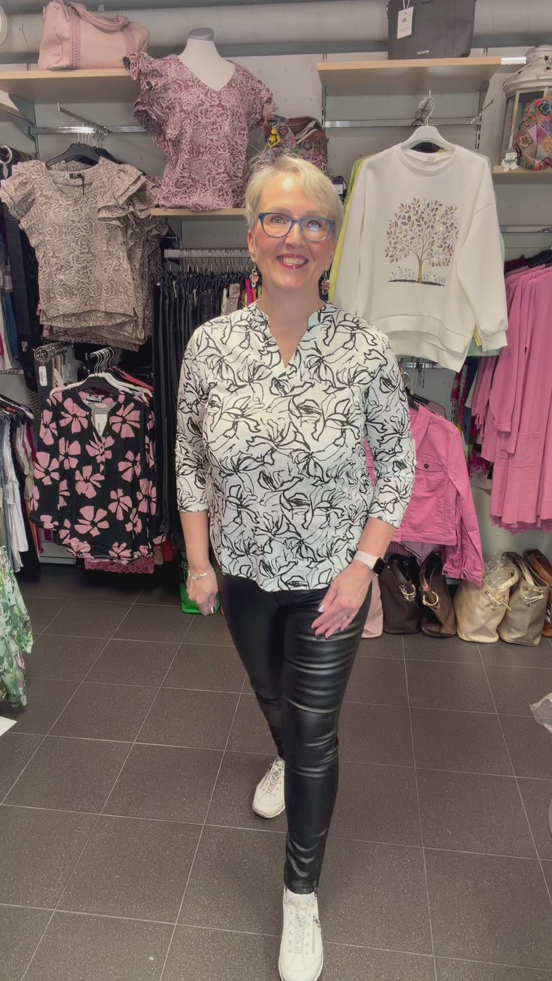 Naisten mustavalkoinen paitapusero joustavasta materiaalista, V-pääntie ja pieni kaulus, vajaamittaiset hihat ja kaareva helma