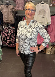 Naisten mustavalkoinen paitapusero joustavasta materiaalista, V-pääntie ja pieni kaulus, vajaamittaiset hihat ja kaareva helma