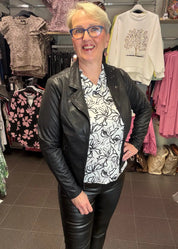 Naisten mustavalkoinen paitapusero joustavasta materiaalista, V-pääntie ja pieni kaulus, vajaamittaiset hihat ja kaareva helma