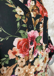 Naisten musta kukkakuvioinen paitapusero, kevyt ja boheemi V-pääntiellä, nappirivillä ja tamppihihoilla.