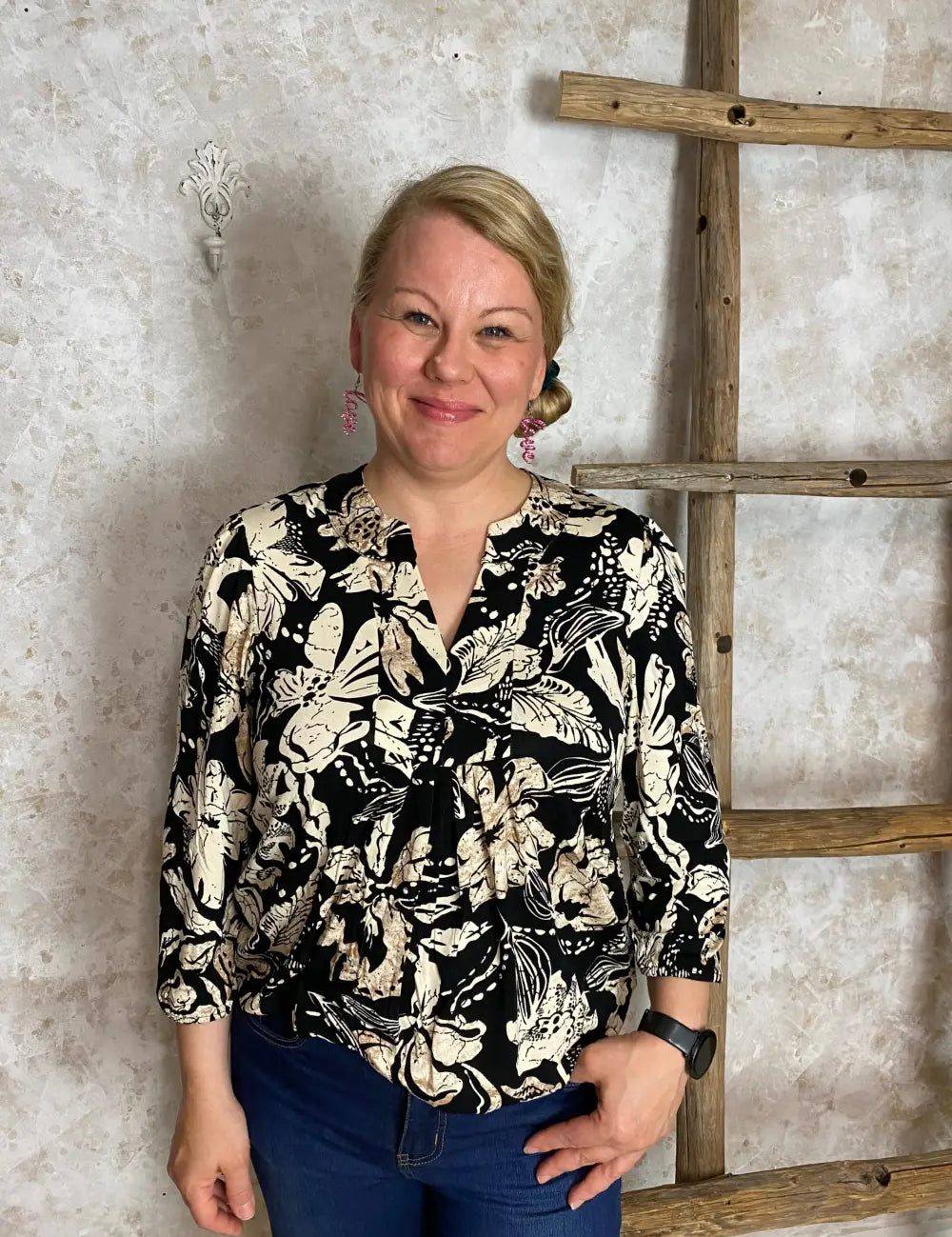 Hiekanvärinen kuviollinen pusero, jossa pieni V-aukko, vyötärölaskokset, vajaamittaiset puhvihihat ja pussimainen helma
