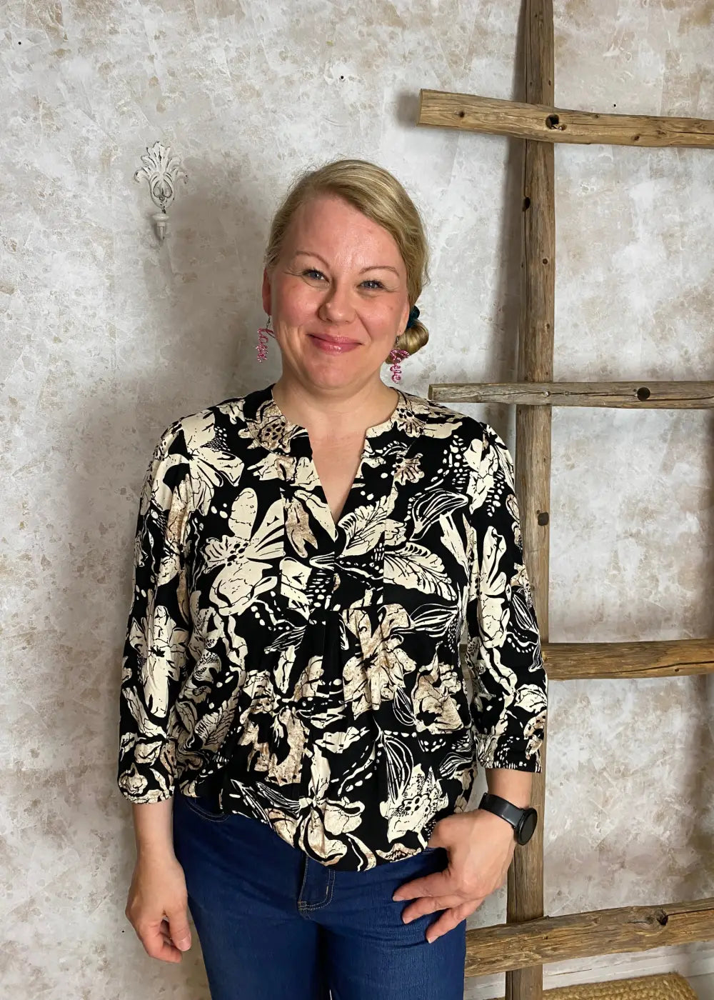 Hiekanvärinen kuviollinen pusero, jossa pieni V-aukko, vyötärölaskokset, vajaamittaiset puhvihihat ja pussimainen helma