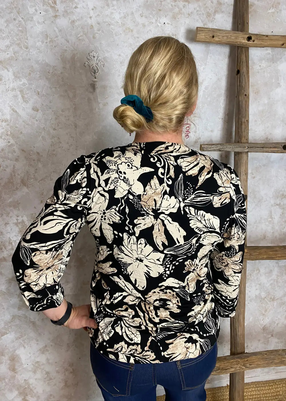 Hiekanvärinen kuviollinen pusero, jossa pieni V-aukko, vyötärölaskokset, vajaamittaiset puhvihihat ja pussimainen helma