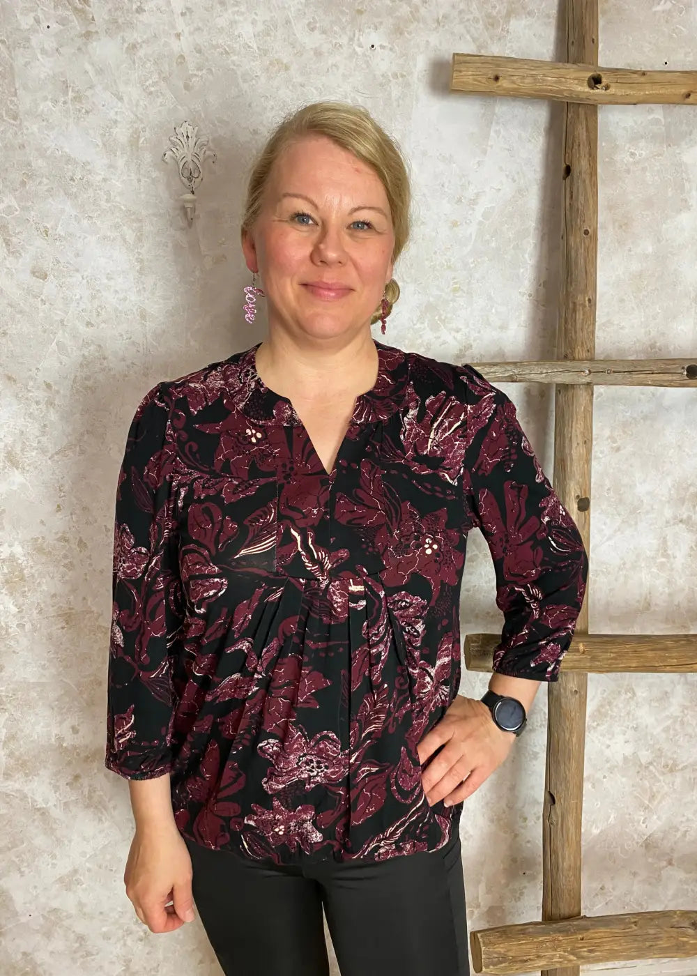 Viininpunainen kuviollinen pusero, jossa pieni V-aukko, vyötärölaskokset, vajaamittaiset puhvihihat ja pussimainen helma