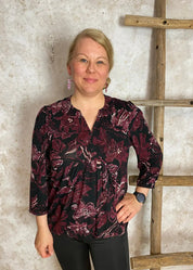 Viininpunainen kuviollinen pusero, jossa pieni V-aukko, vyötärölaskokset, vajaamittaiset puhvihihat ja pussimainen helma