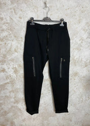 Reisitaskuhousut joustavasta materiaalista, korkea vyötärö leveällä kuminauhalla ja kiristysnauhoilla, kapenevat lahkeet ja edessä taskut